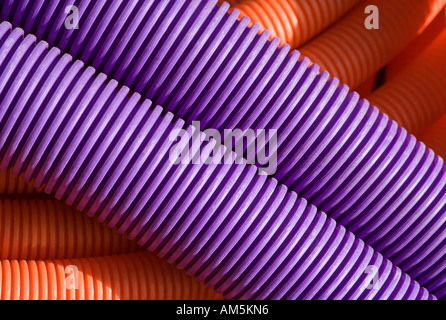 Flexible purple and orange corrugated mantle pipe duct cable coils. Tubing used as conduit for high speed cable and fibre optic Stock Photo