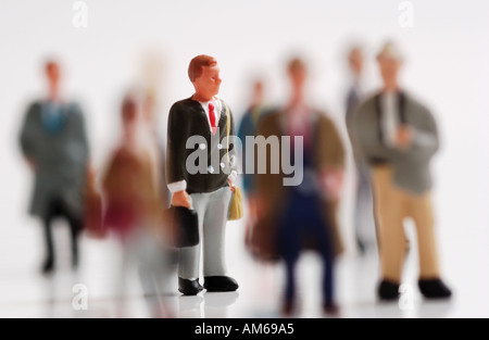 Crowd of businesspeople figures selectively focused on businessman in middle with briefcase Stock Photo