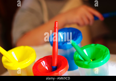 Yellow Blue Green and Red paints with kid painting in background Stock Photo