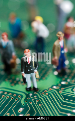 Crowd of businessmen figures standing on computer circuit board selectively focused on one businessman in foreground Stock Photo