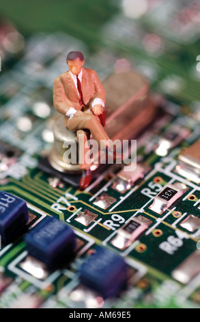 Businessman figure sitting on circuit board Stock Photo