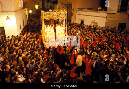 Jerez de la Frontera during the holy week of Eastern a hooded procession is carrying the statue of the Holy Mary Stock Photo