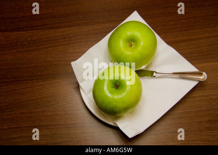 Two green apples, a white napkin and a knife on a plate Stock Photo