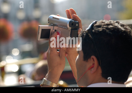 Man using digital video camcorder on open top of tourist bus, UK Stock Photo