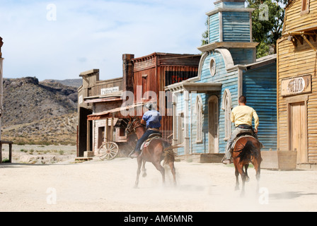 Two cowboys riding away in a traditional American western style town Stock Photo