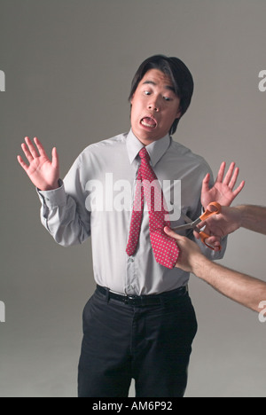 Businessman with tie being cut depicting demotion emasculation Stock Photo