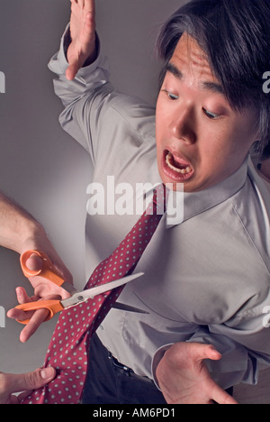 Close up of businessman with tie being cut depicting demotion emasculation Stock Photo