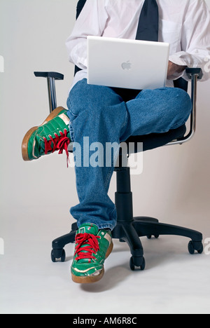 Young executive in casual attire blue jeans and green tennis shoes with red laces Stock Photo