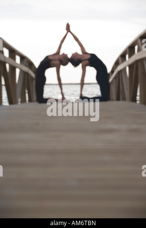 two women practise yoga pose together Stock Photo