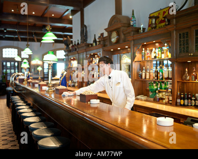 A bartender wipes the bar counter in Raffles Hotel Singapore Stock Photo