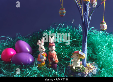A cute Easter-themed still life image using home holiday decorations and knick knacks. A bunny family stands under an egg tree. Stock Photo