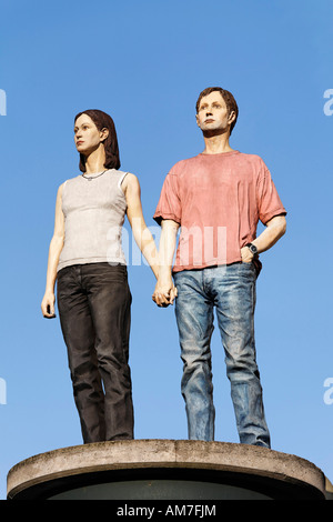 Young couple holding hands, sculpture standing at the top of a advertising column, Duesseldorf, NRW, Germany Stock Photo