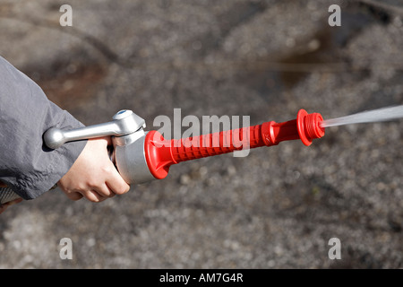 Little boy playing fire brigade, spraying with professional hose, Germany Stock Photo