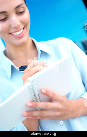 Businesswoman writing on notebook, smiling Stock Photo