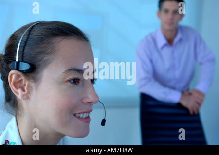 Businesswoman using headset with colleague standing in background Stock Photo