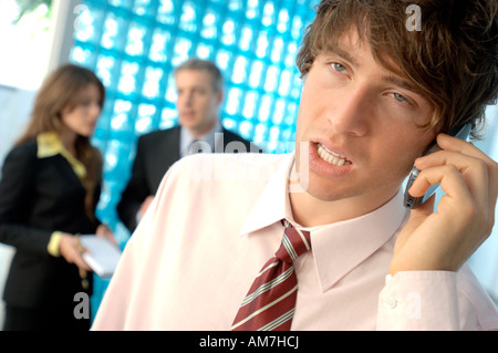 Businessman using mobile phone with colleagues in background Stock Photo