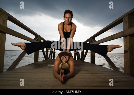 two women friends doing yoga postures in nature Stock Photo