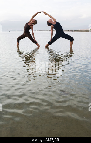 couple of women doing a yoga pose in water Stock Photo