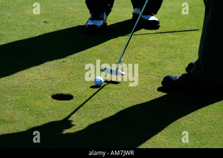 Two golfers putting on a golf course Stock Photo