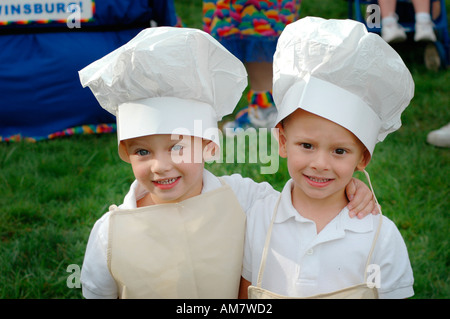 Twin kids children looking alike and like cooks with tall hats Stock Photo