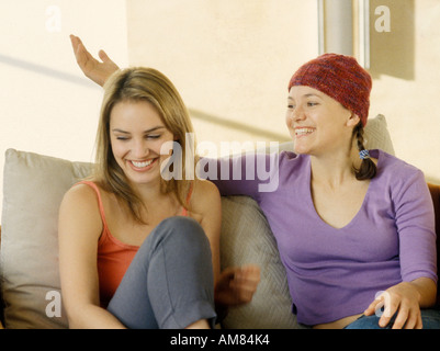 Young women sitting on sofa, smiling Stock Photo
