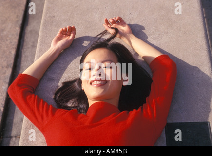 Young woman lying on road, smiling Stock Photo