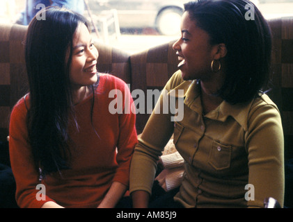Young women sitting on sofa, laughing Stock Photo
