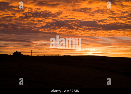 dh  ORPHIR ORKNEY Cottage silhouette and cloudscape sunset sky scottish croft fiery dusk orange clear red clouds highlands house uk scotland Stock Photo