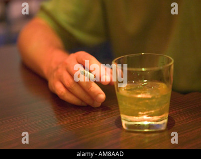 Person smoking cigarette Glass of whisky standing near Stock Photo