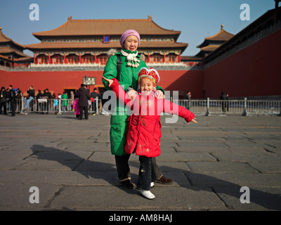 A woman and a girl in winter coats pose for pictures inside the Forbidden City in Beijing, China. Stock Photo