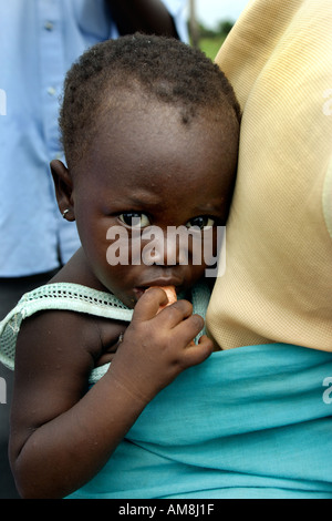 Fada N Gourma Burkina Faso August 23rd 2005 A baby eats a carrot like sweet potato whilst carried in sling on his mothers bac Stock Photo