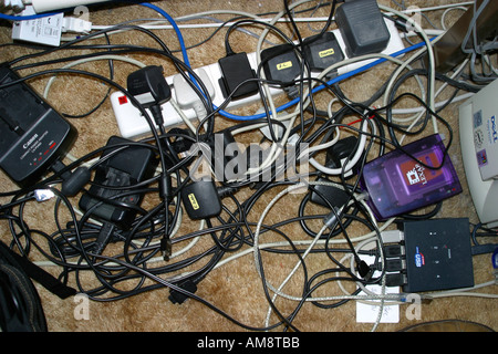 Jumble of tangled wires sockets and plugs in home office Stock Photo