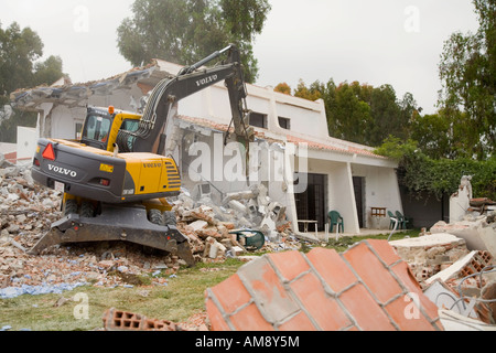 Demolition of old buildings with aid of mechanical excavator Stock Photo