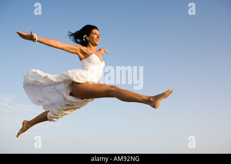Woman in white dress jumping in the air Stock Photo