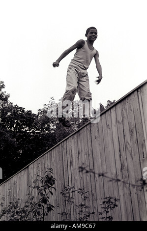 Young boy walking along the fence. Stock Photo