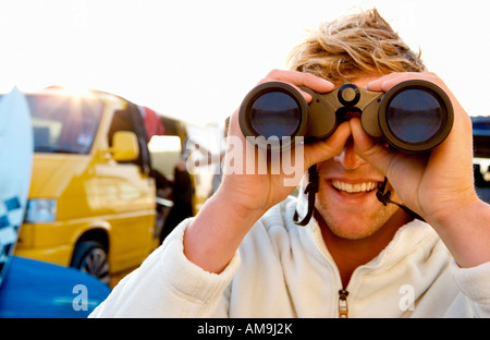 Man on beach with binoculars smiling with woman unloading van at the beach . Stock Photo