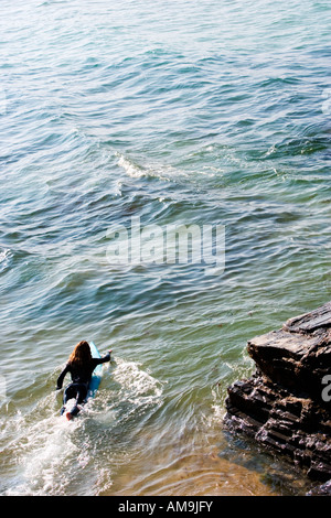 Woman lying on surfboard in the water. Stock Photo