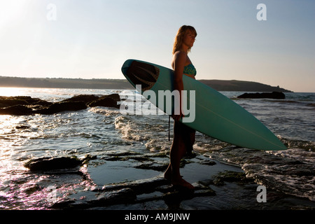 Woman standing in shallow water with surfboard. Stock Photo