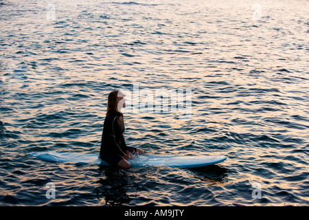 Woman sitting on surfboard in the water. Stock Photo