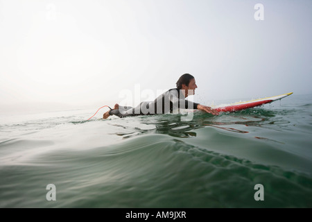 Man lying on surfboard in the water. Stock Photo