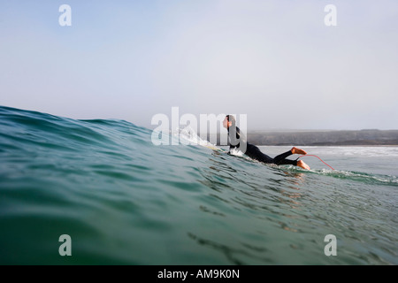 Man getting up on a surfboard in the water. Stock Photo