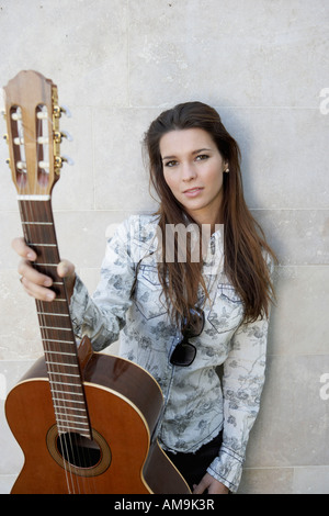 Woman standing and holding up a guitar.