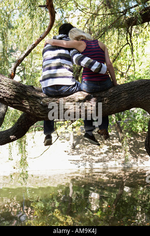 Couple sitting in a tree by a lake. Stock Photo