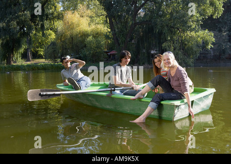 Four friends in a rowboat smiling. Stock Photo