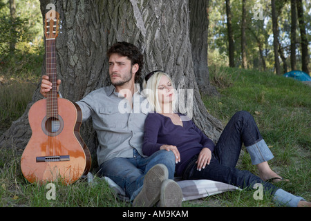 Man holding a guitar with sleeping woman leaning on him. Stock Photo