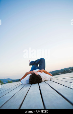 Man lying on dock outdoors. Stock Photo