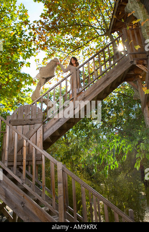 Woman climbs wood outdoor stairway holding blanket. Stock Photo