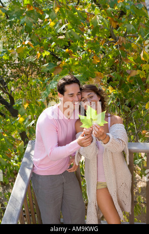 Couple standing on balcony holding leaf smiling. Stock Photo