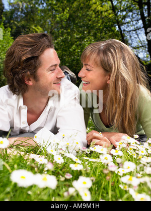 Couple lying in the grass smiling at each other. Stock Photo
