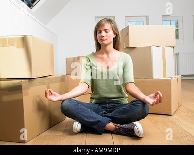 Woman doing yoga with moving boxes around her. Stock Photo